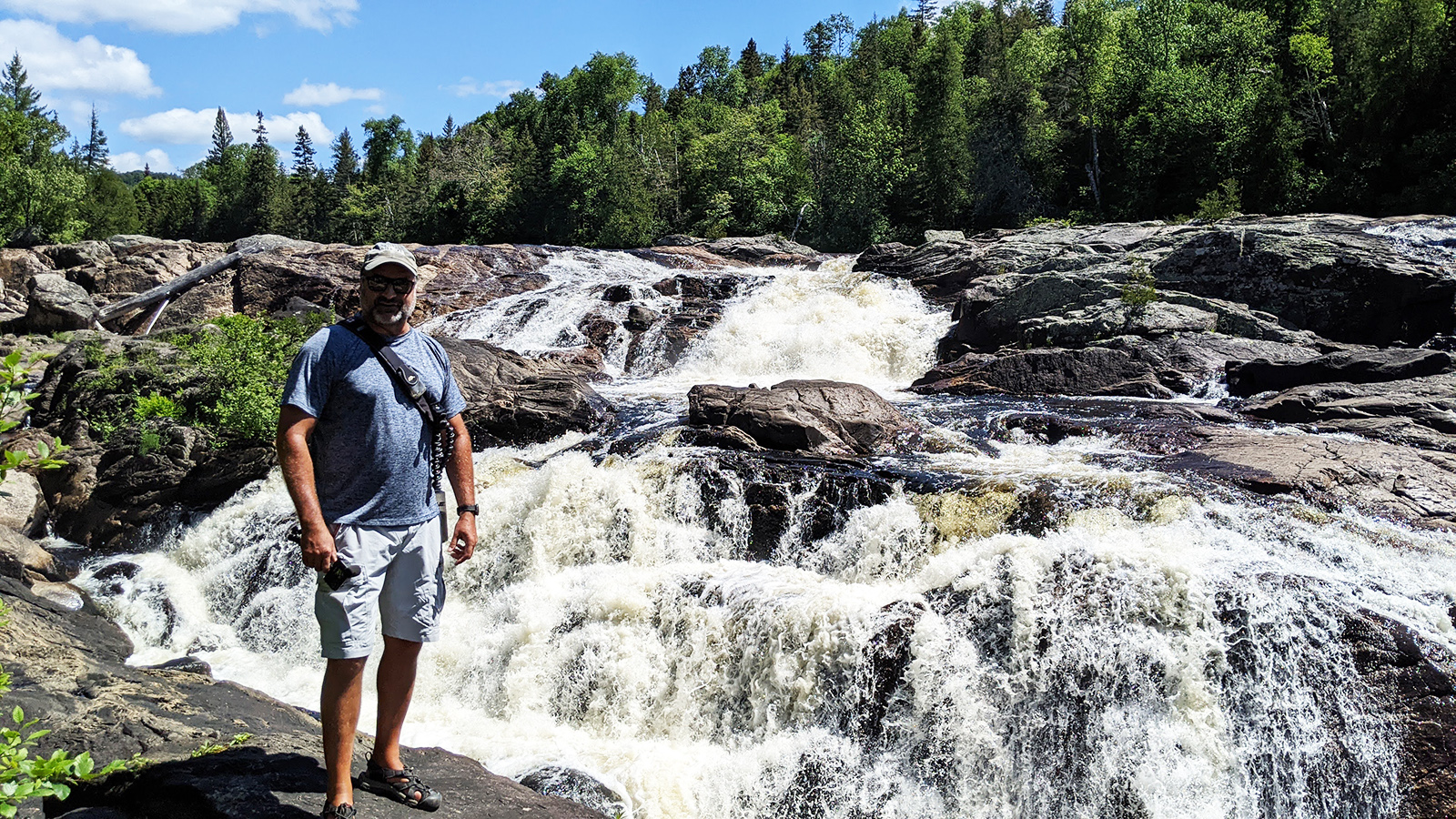 Ben Coles posing still with the aggressive rapids of Lady Evelyn Falls.